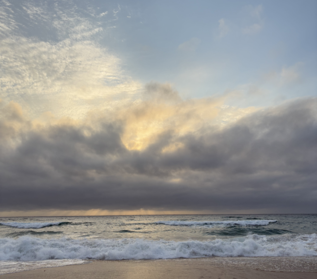 A serene beach scene with gentle ocean waves under a clear sky.